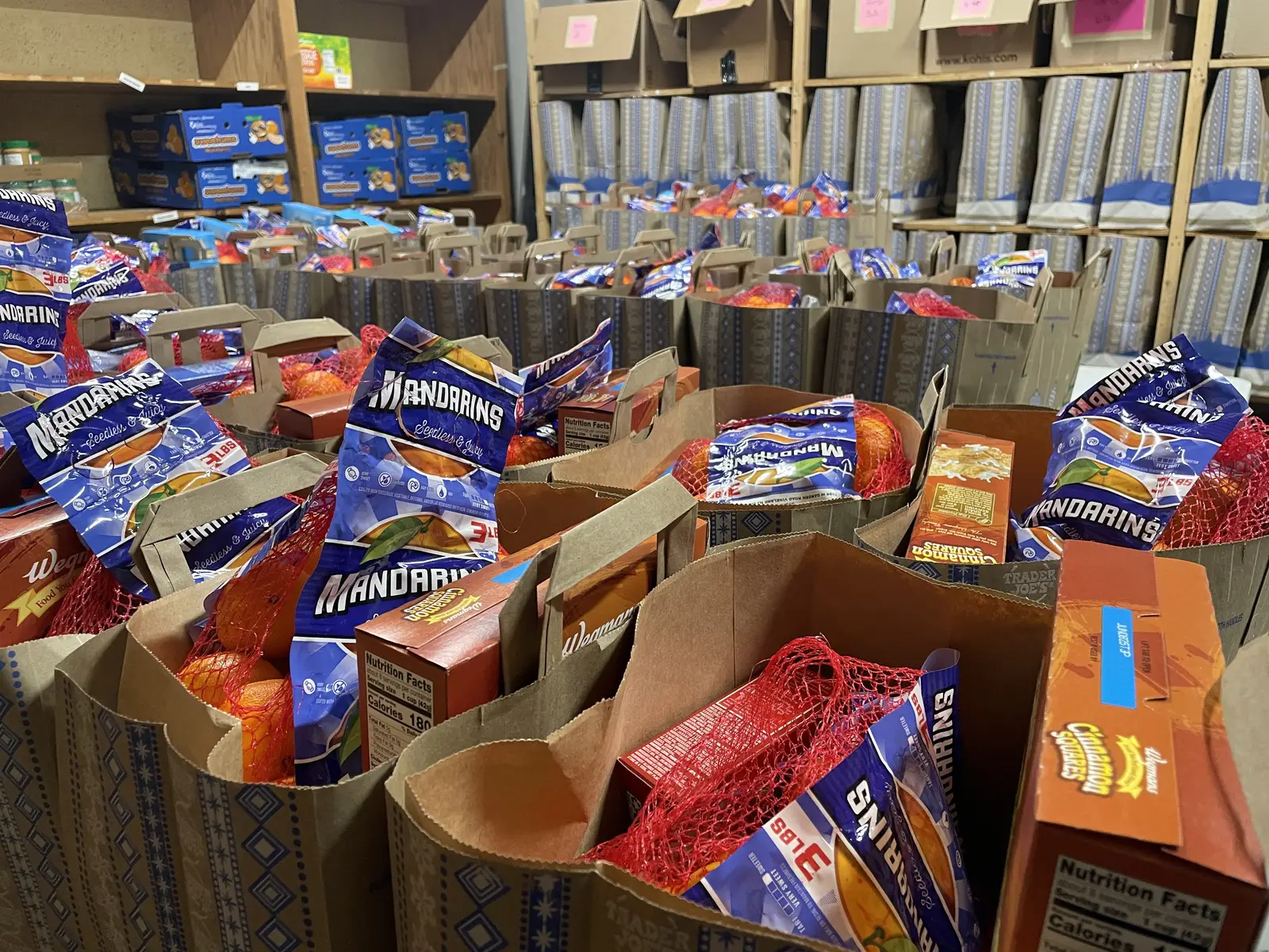 Grocery bags packed with mandarin oranges, cereal, and cookies in the SpotMart pantry